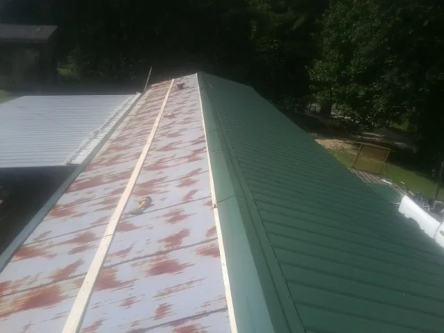 Old rusted panels beside newly installed green metal roofing — Wind Damage Roof Repair by Roofing Brothers in Welcome